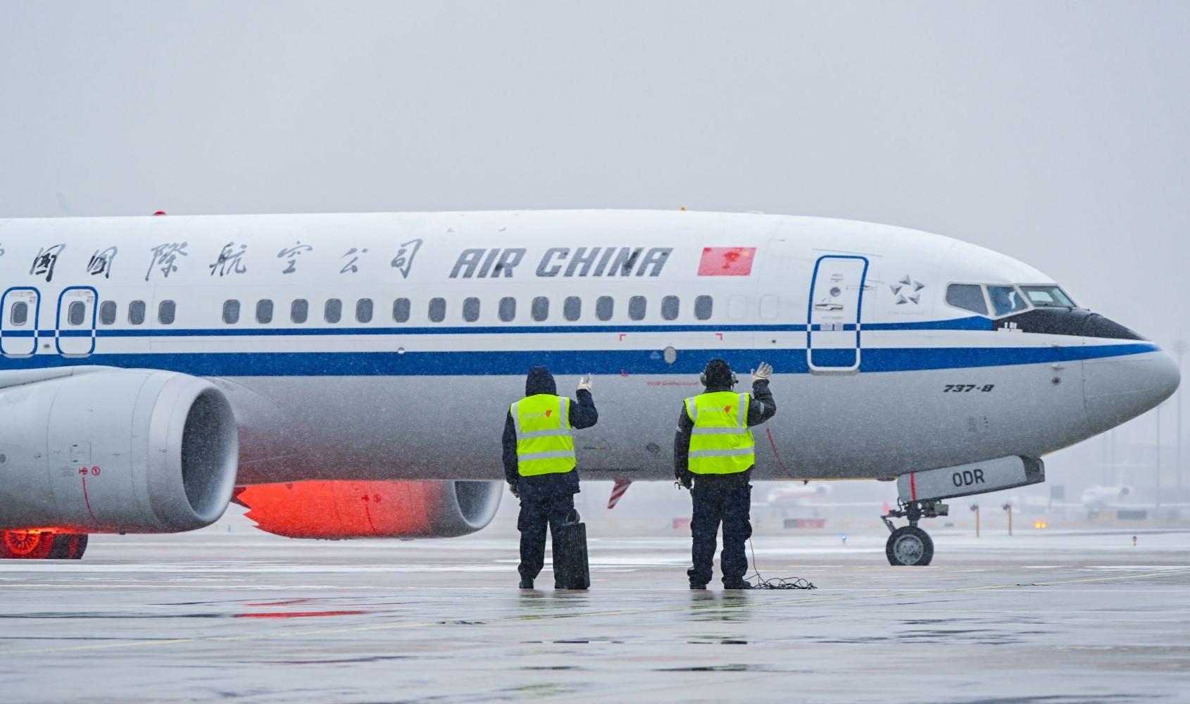 在北京首都國際機場，中航集團一線工作人員目送完成除冰雪作業(yè)的飛機緩緩出港。