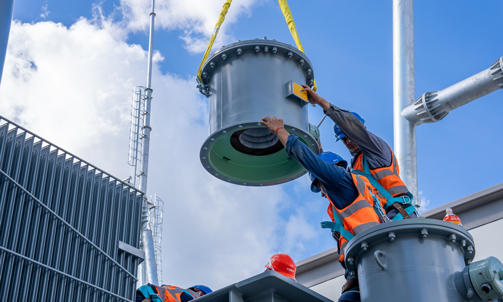 中老500千伏聯網工程老撾段包括新建一座變電站及32.5公里線路，計劃于2026年4月投產。目前，變電站主體結構及“三通一平”已完成，主要設備全部到場，正進行電氣安裝。圖為施工人員開展主變套管底座安裝作業。 