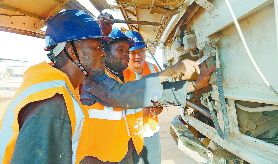 在安哥拉二期大市政項目建設中，為確保工程如期履約，中國鐵建所屬中鐵十四局通過開展技術革新、提高機械設備能效、大量聘用當?shù)毓と说却胧燃涌炝斯こ踢M度，又節(jié)約了施工成本，為解決當?shù)鼐蜆I(yè)、加快經(jīng)濟發(fā)展作出了積極貢獻，贏得了當?shù)鼐用窈驼暮迷u。圖為當?shù)貢r間10月28日，安籍員工在中方技術人員指導下檢修施工車輛。（周存泉 攝）